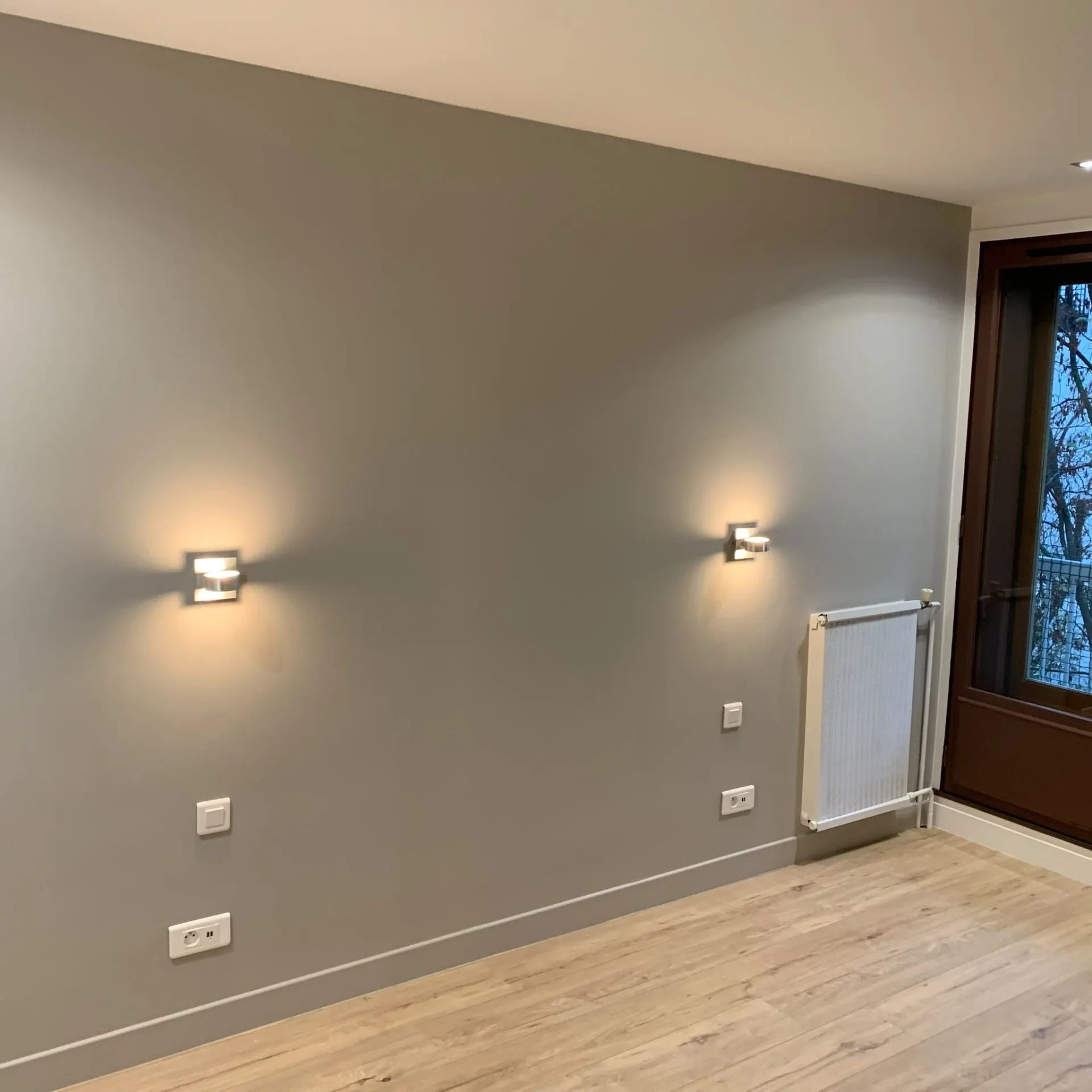 Chambre rénovée par UMPT avec radiateur, appliques et sol stratifié
