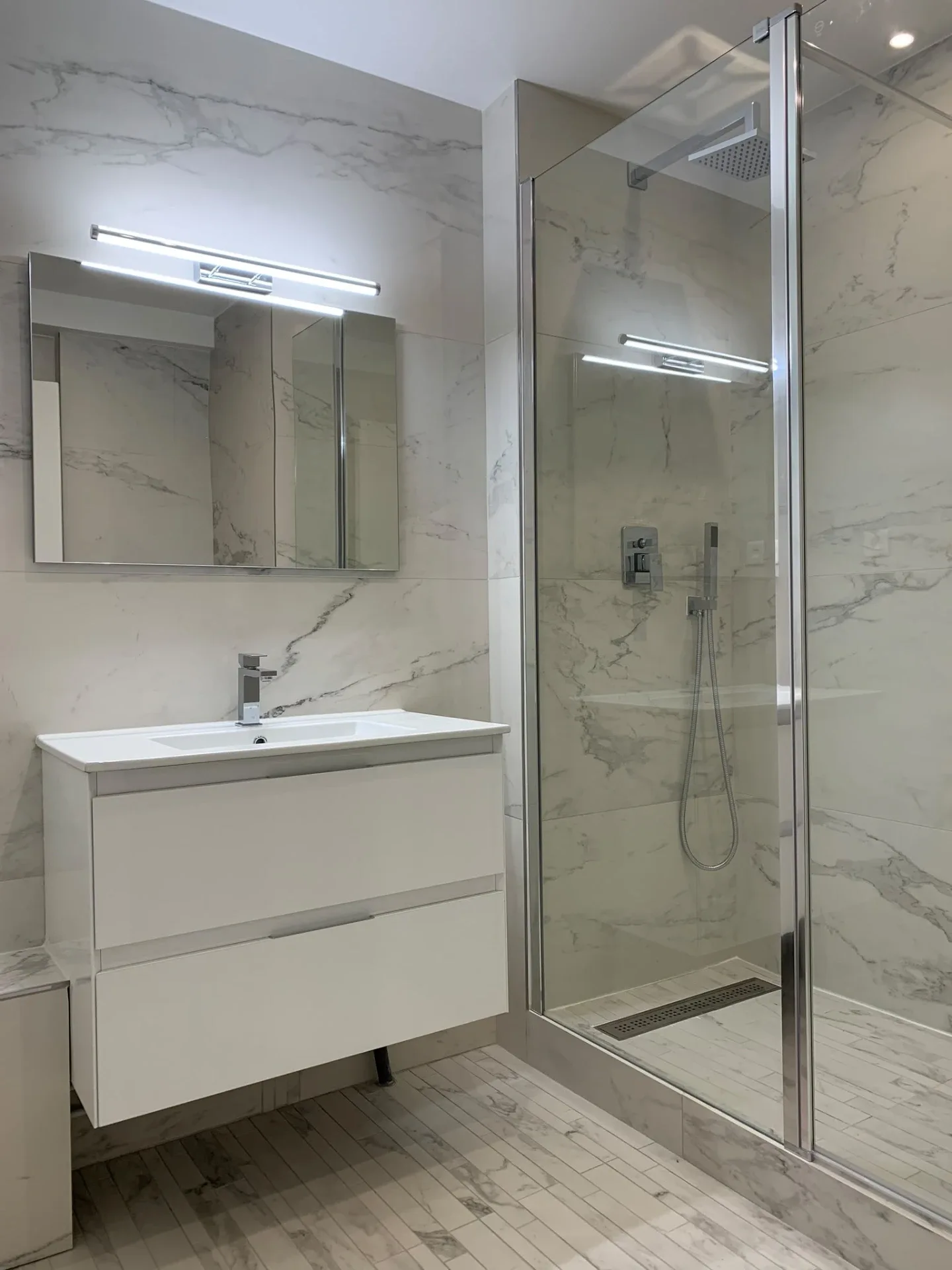 Salle de bains rénovée par UMPT : douche à l'italienne vitrée, meuble vasque, carrelage effet marbre